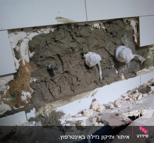 קיר פתוח עם צנרת מכוסה בטיח ותיקונים